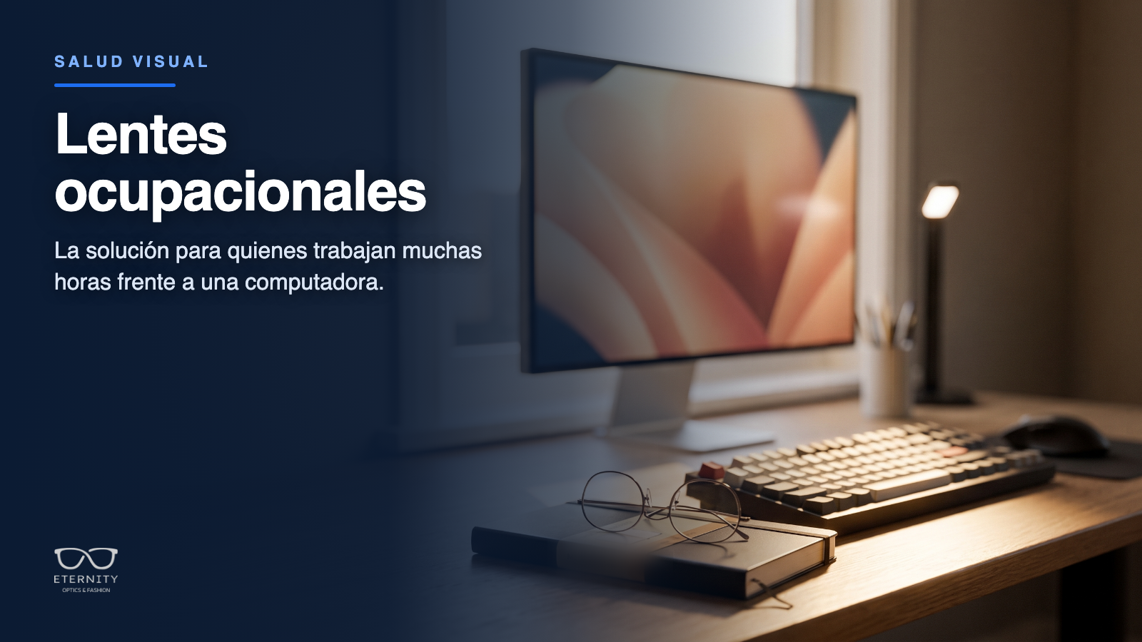 Escritorio con monitor, teclado y anteojos apoyados sobre una libreta, junto a una ventana con luz natural